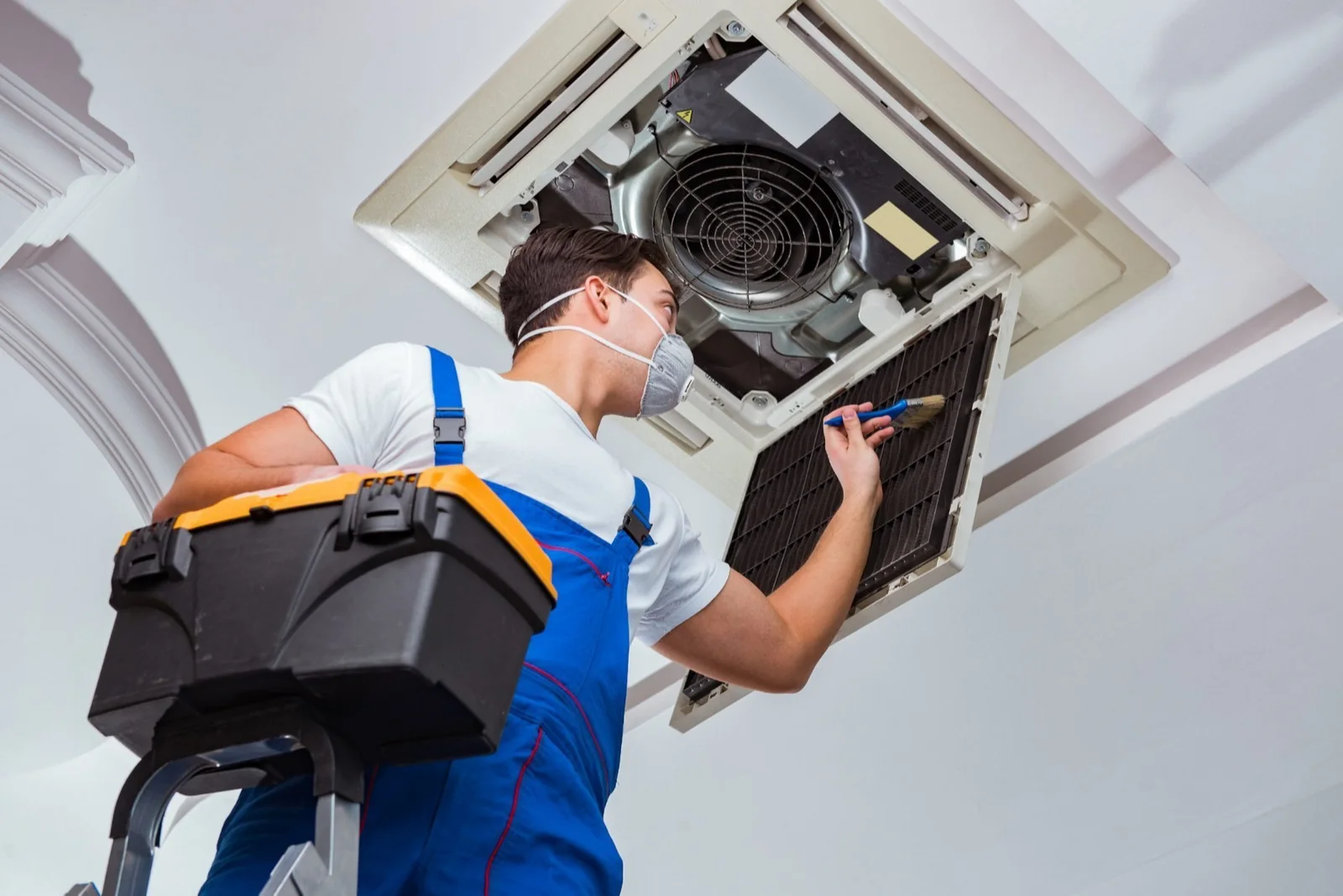 HVAC technician inspecting ceiling-mounted cooling equipment